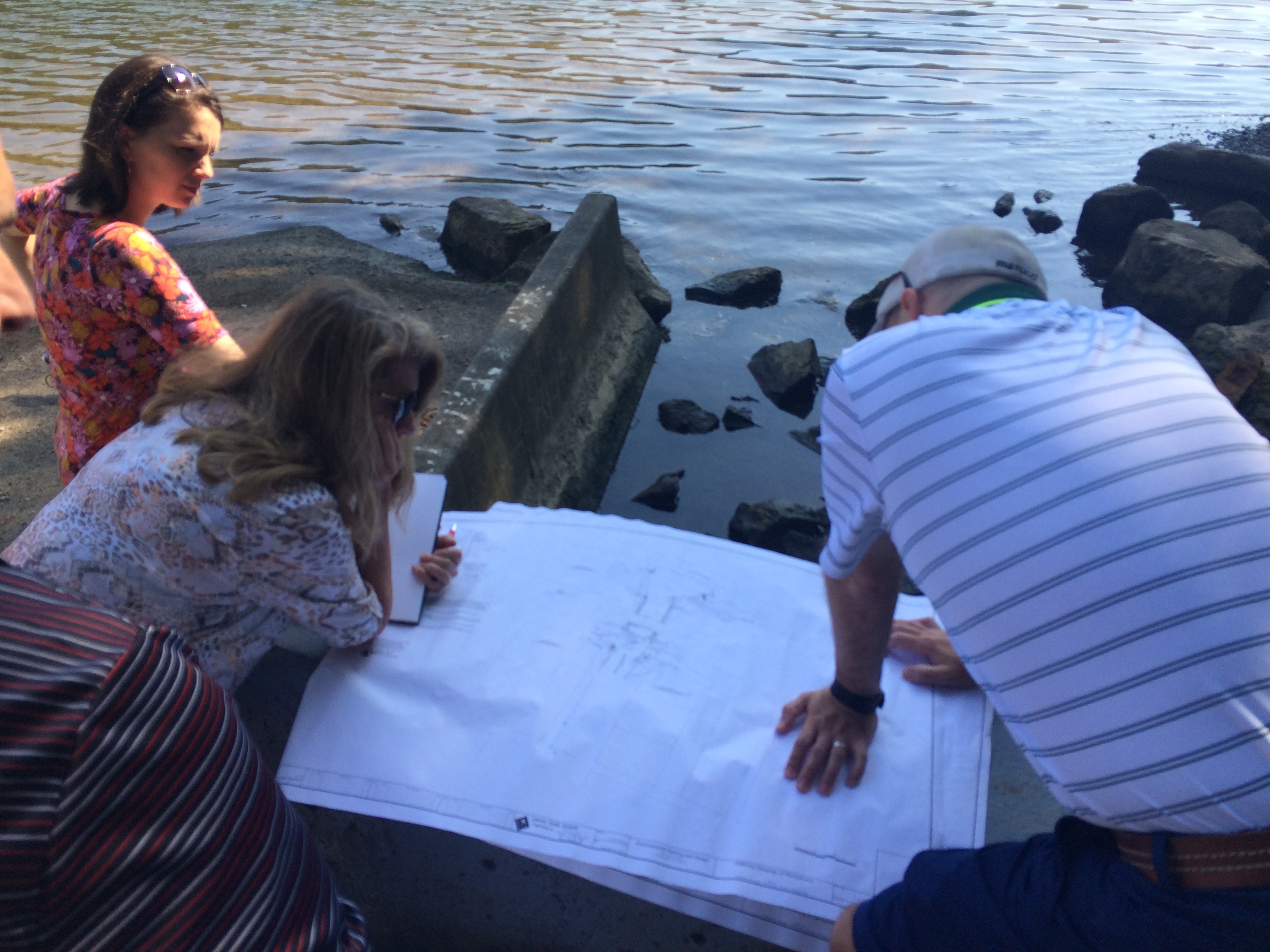 Three people huddle over a map near the river