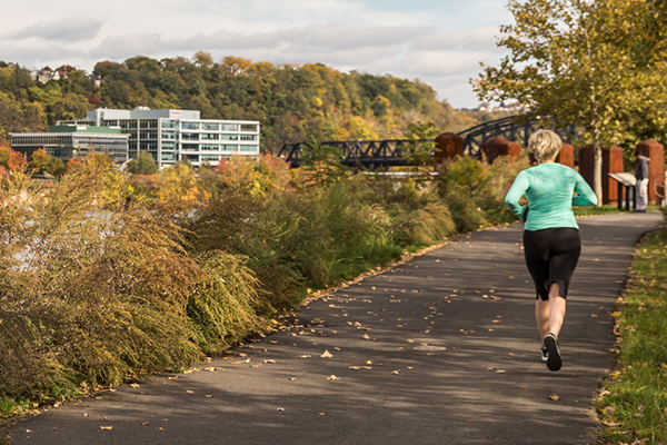 A woman jogs along the Three Rivers Heritage trail in autumn.