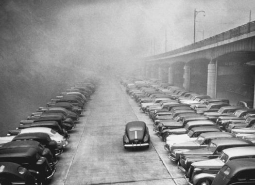 Black and white historic photo of retro cars parked on a polluted Mon Wharf.