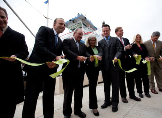 Photo of elected officials cutting a green ribbon on the Mon Wharf Landing.