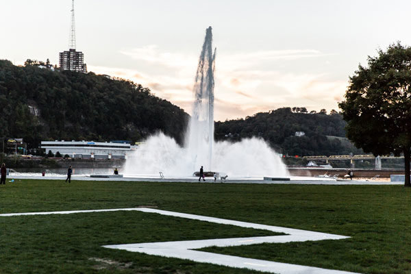 View of the Great Lawn with green grass and a concrete tracery path leading to the fountain.