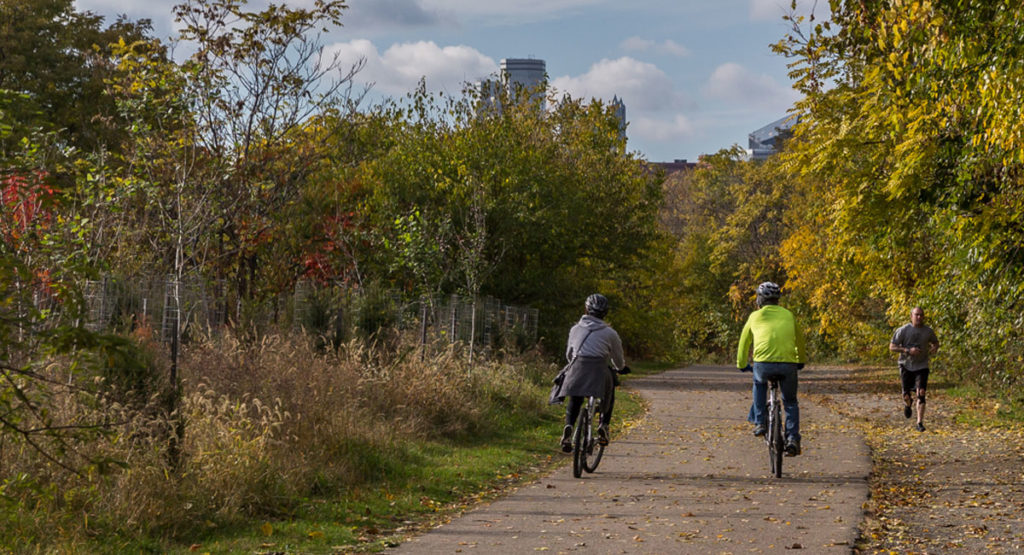 Photo showing two cyclists and a jogger on the South Side trail during autum