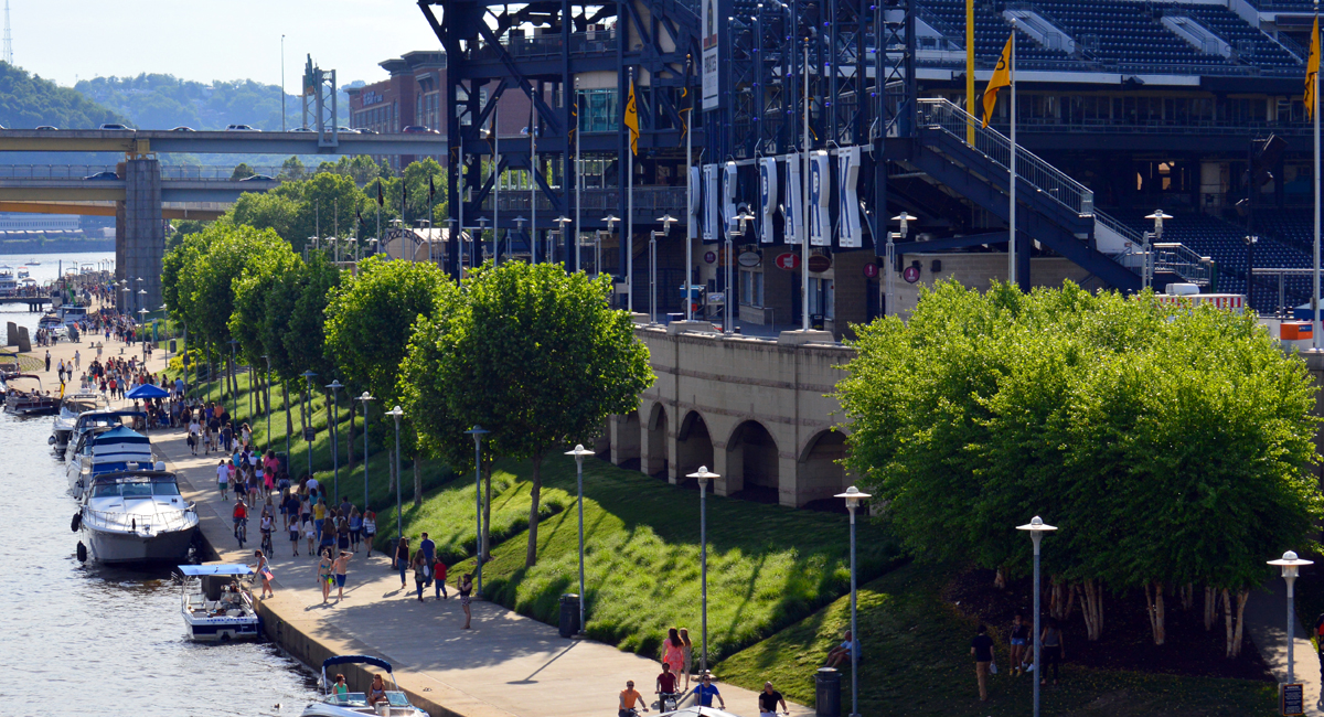 North Shore riverwalk full of pedestrians and boaters near PNC Park