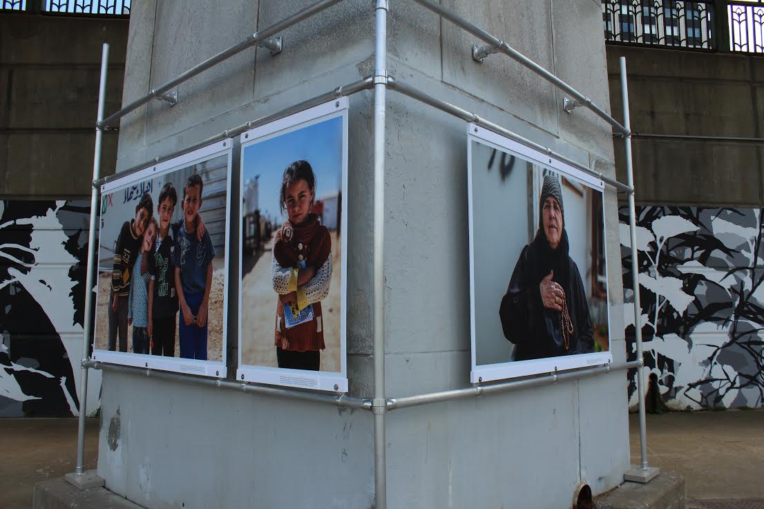 "Displaced" photos by Maranie Staab are shown in front of Kim Beck's "Adjutant" mural.