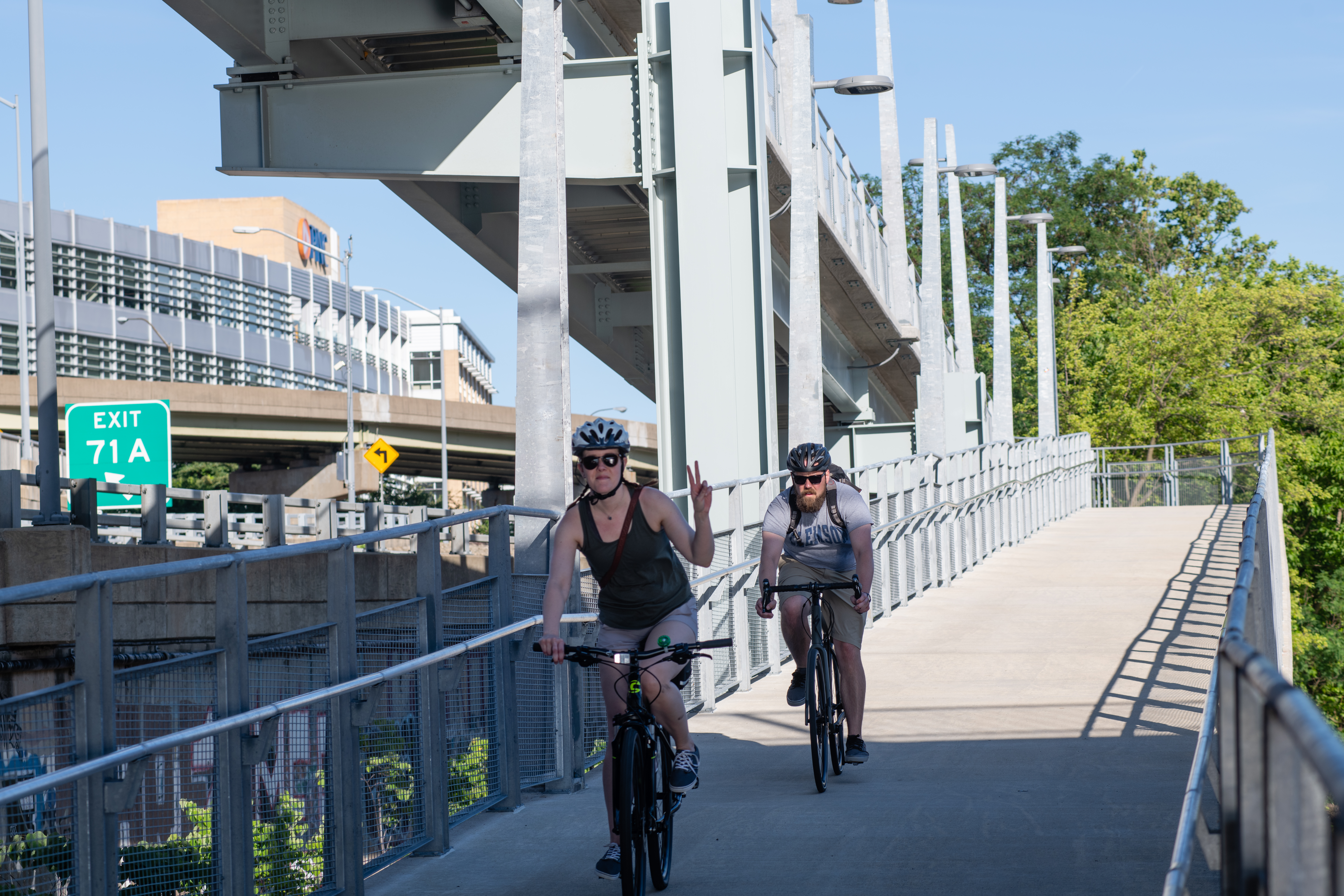 Mon Wharf Switchback ramp shown with two descending bicycle riders, one of whom is flashing a peace sign