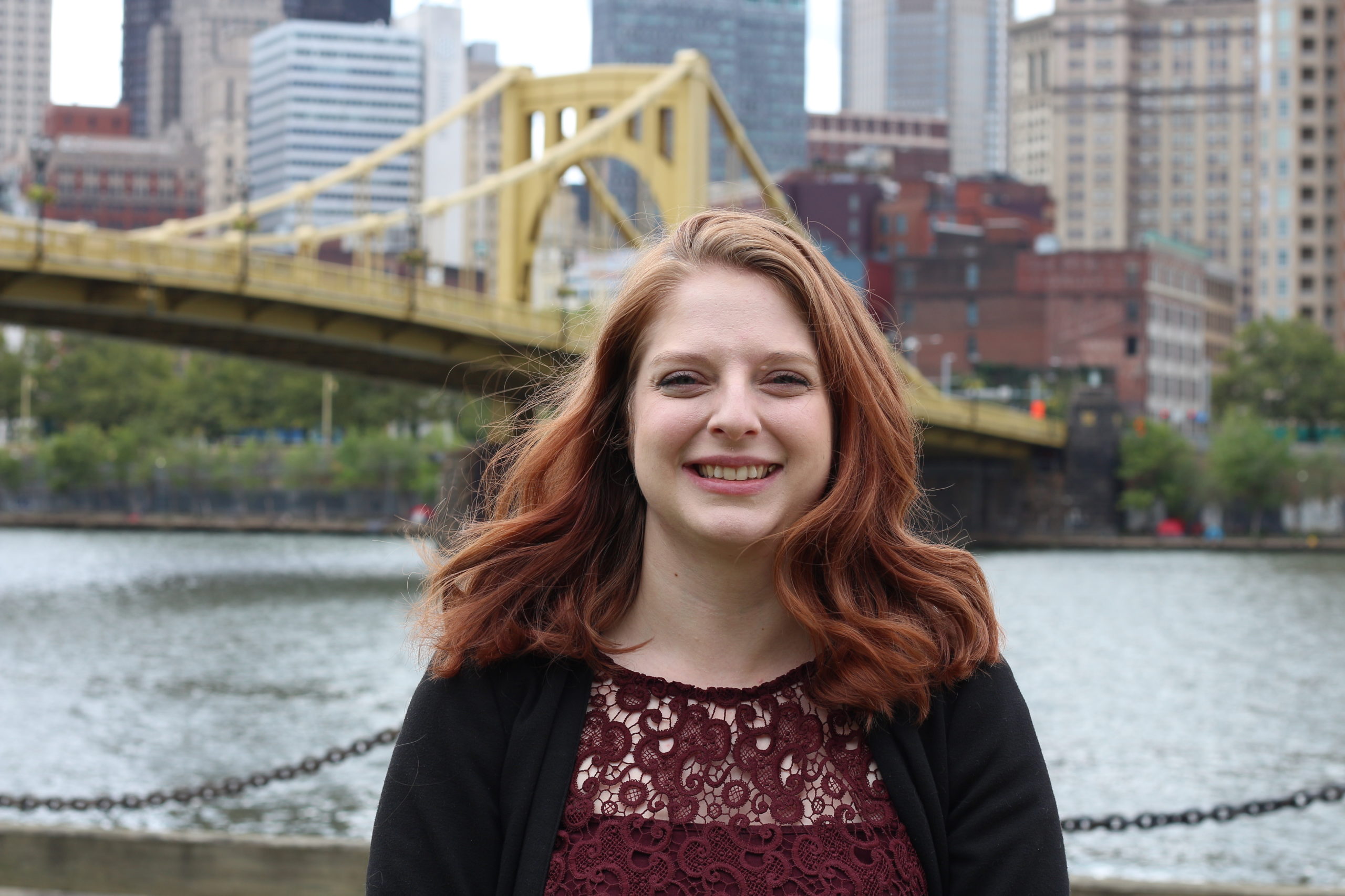 Emily Breedlove in the foreground with the yellow 6th Street Bridge and Pittsburgh skyline in the background